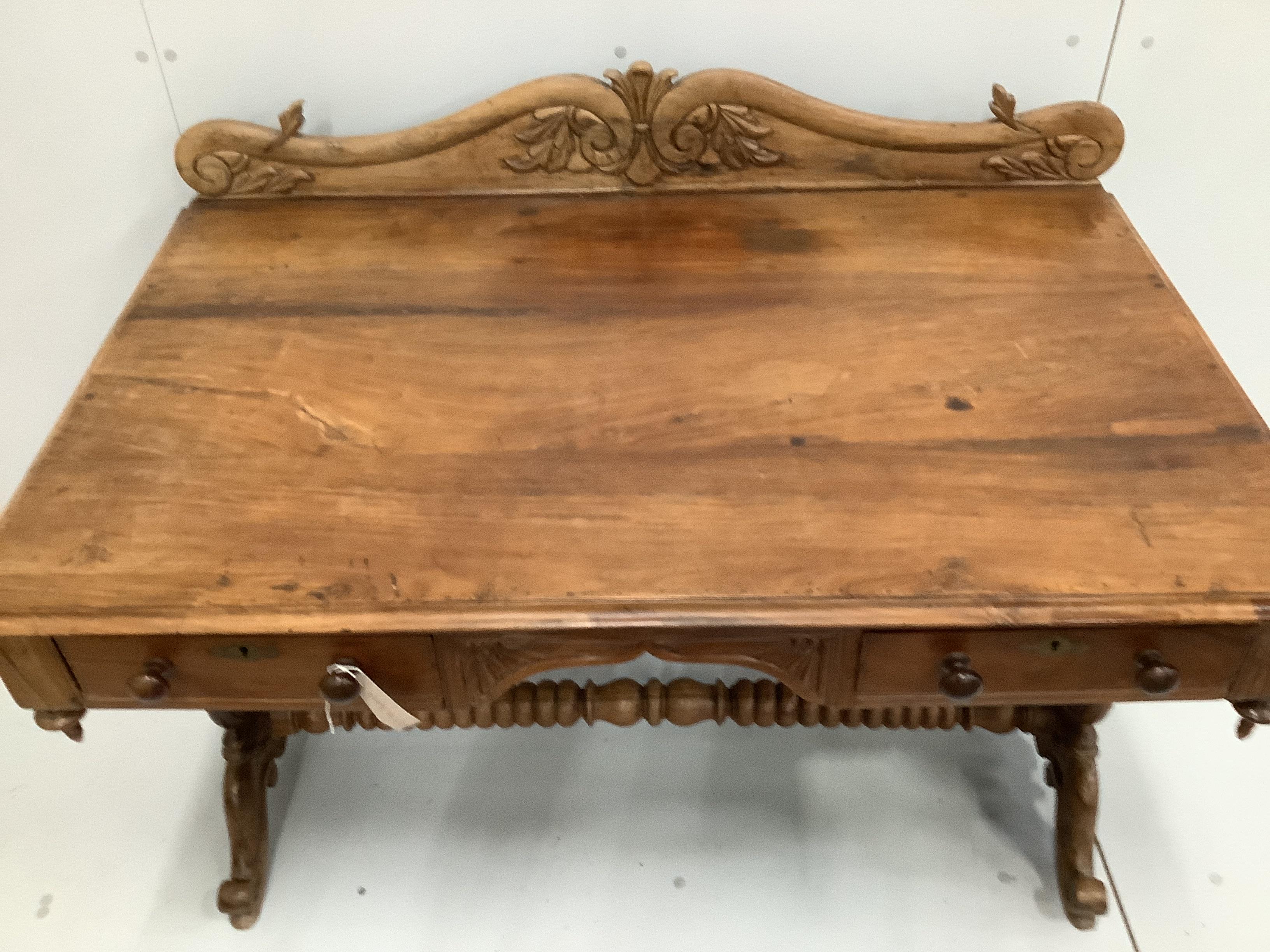An Anglo-Indian carved hardwood writing table, two frieze drawers, on scrolled end supports, width 121cm. depth 74cm, height 92cm